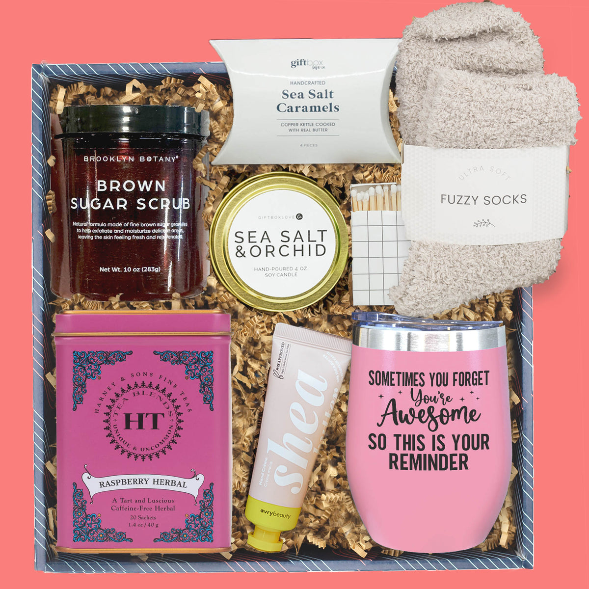 Gift set with brown sugar scrub, sea salt caramels, fuzzy socks, and other items on a pink background