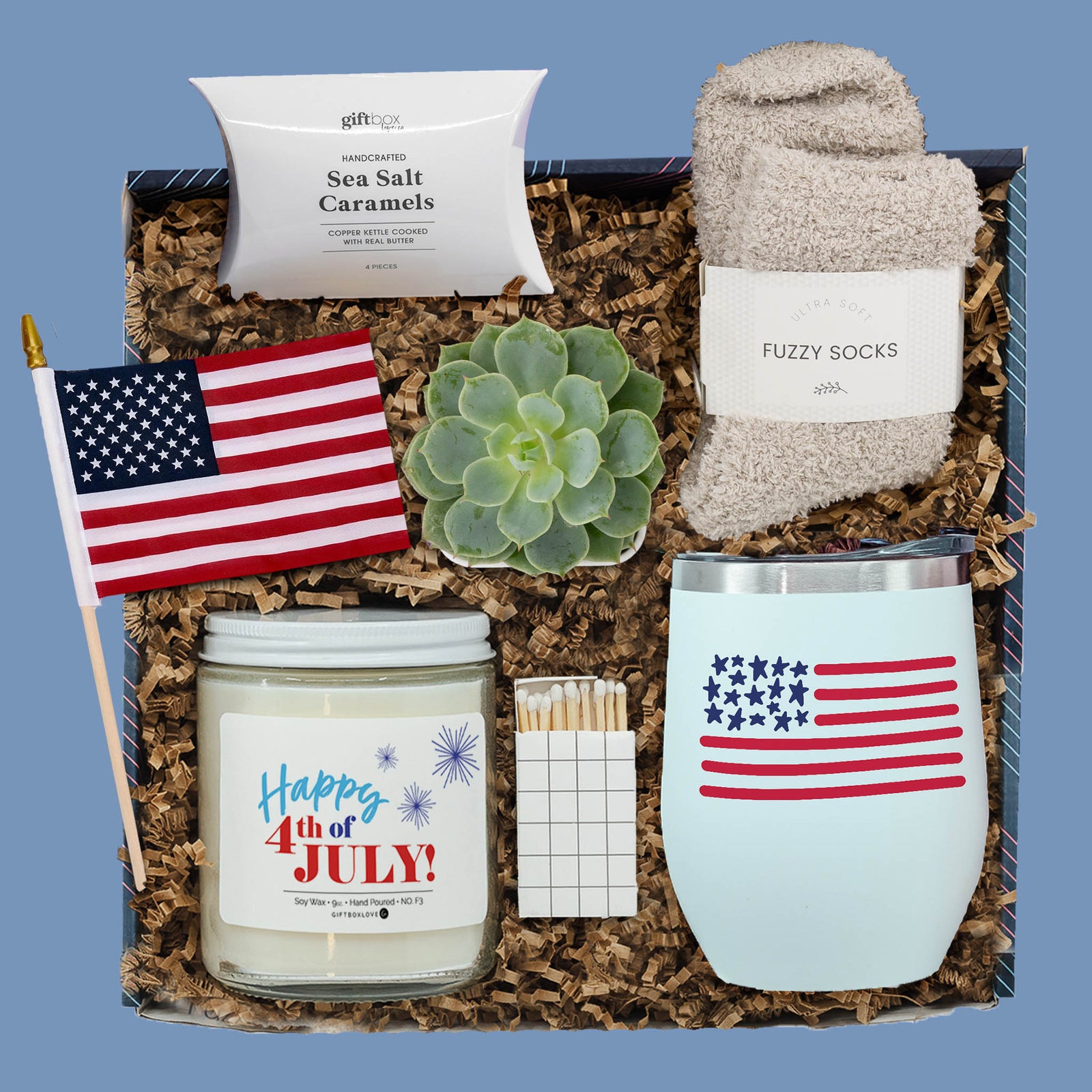 Fourth of July gift box with tumbler, candle, fuzzy socks, succulent, caramels, matchbox, and American flag