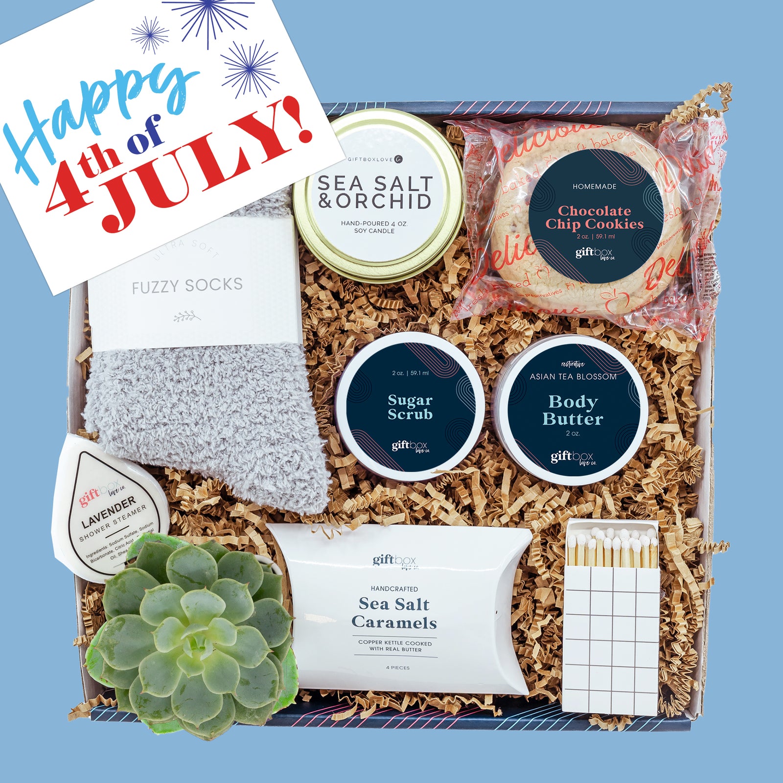 Fourth of July gift box with candle, body care, cookie, fuzzy socks, caramels, succulent, and patriotic card