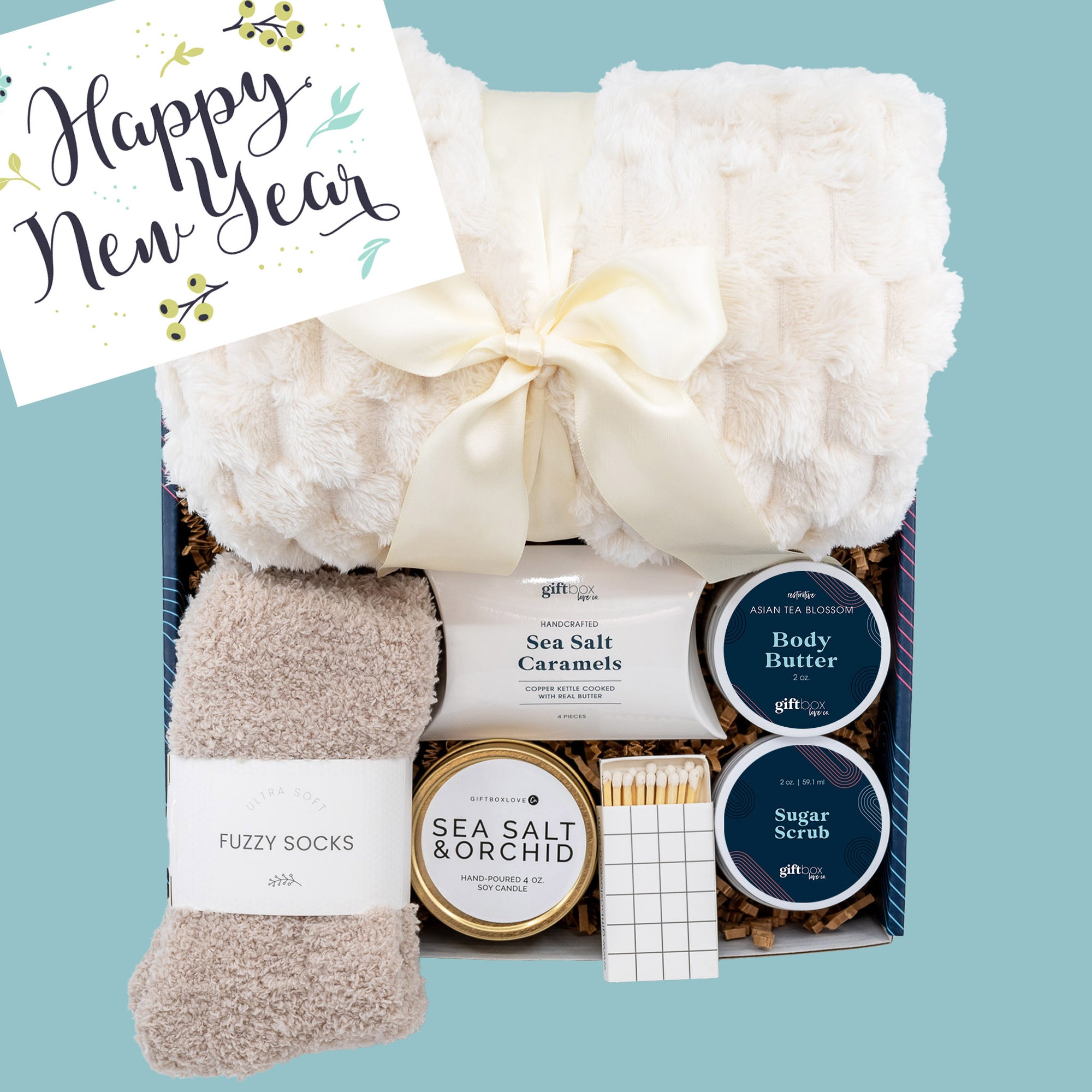 Cozy Gift Box for Women, a perfect Happy New Year gift featuring a blanket, fuzzy socks, candle, caramels, body butter, sugar scrub, and matches