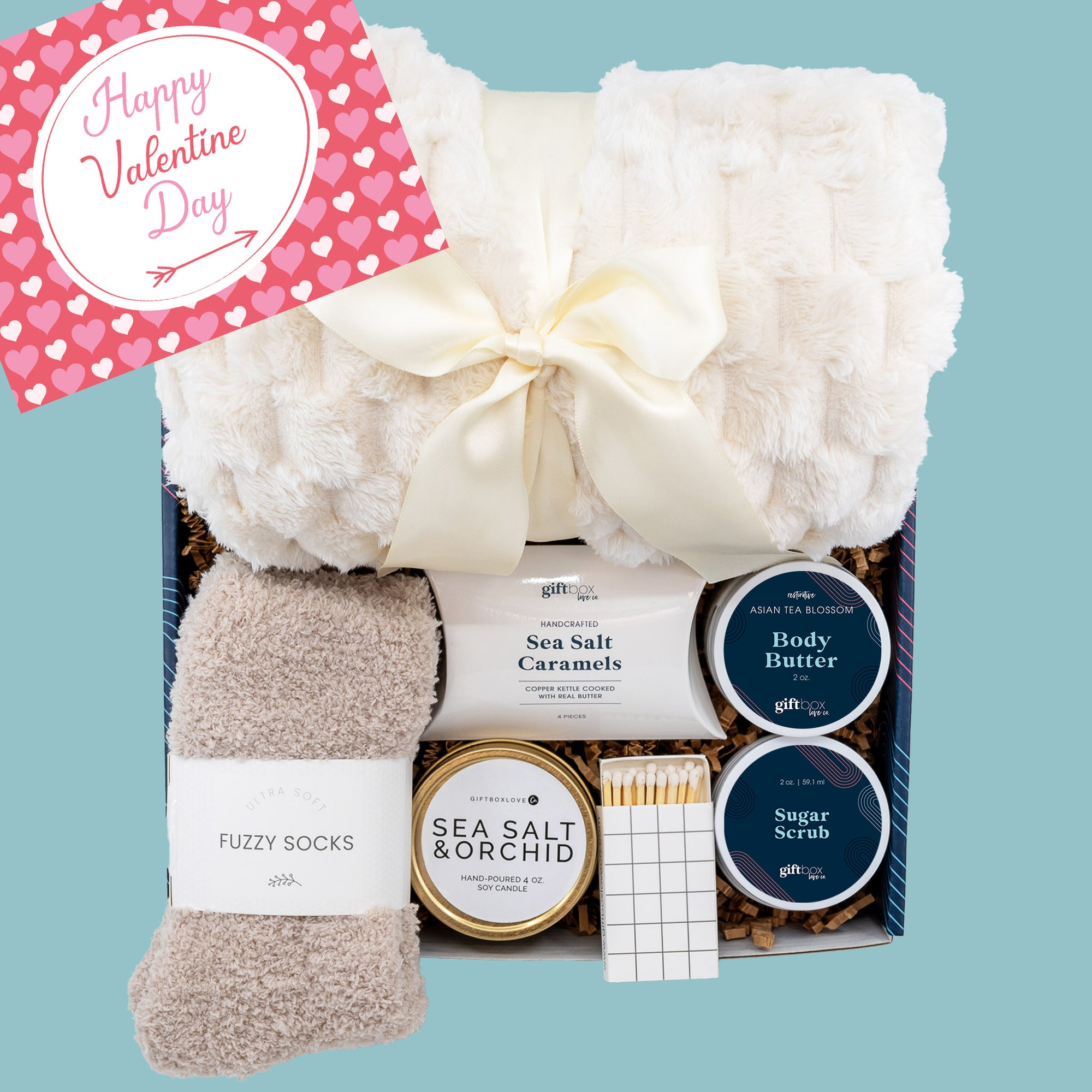 Cozy Valentine’s Gift Box with a cozy blanket, fuzzy socks, scented candle, body butter, sugar scrub, and caramels for the perfect Valentine’s Day gift.