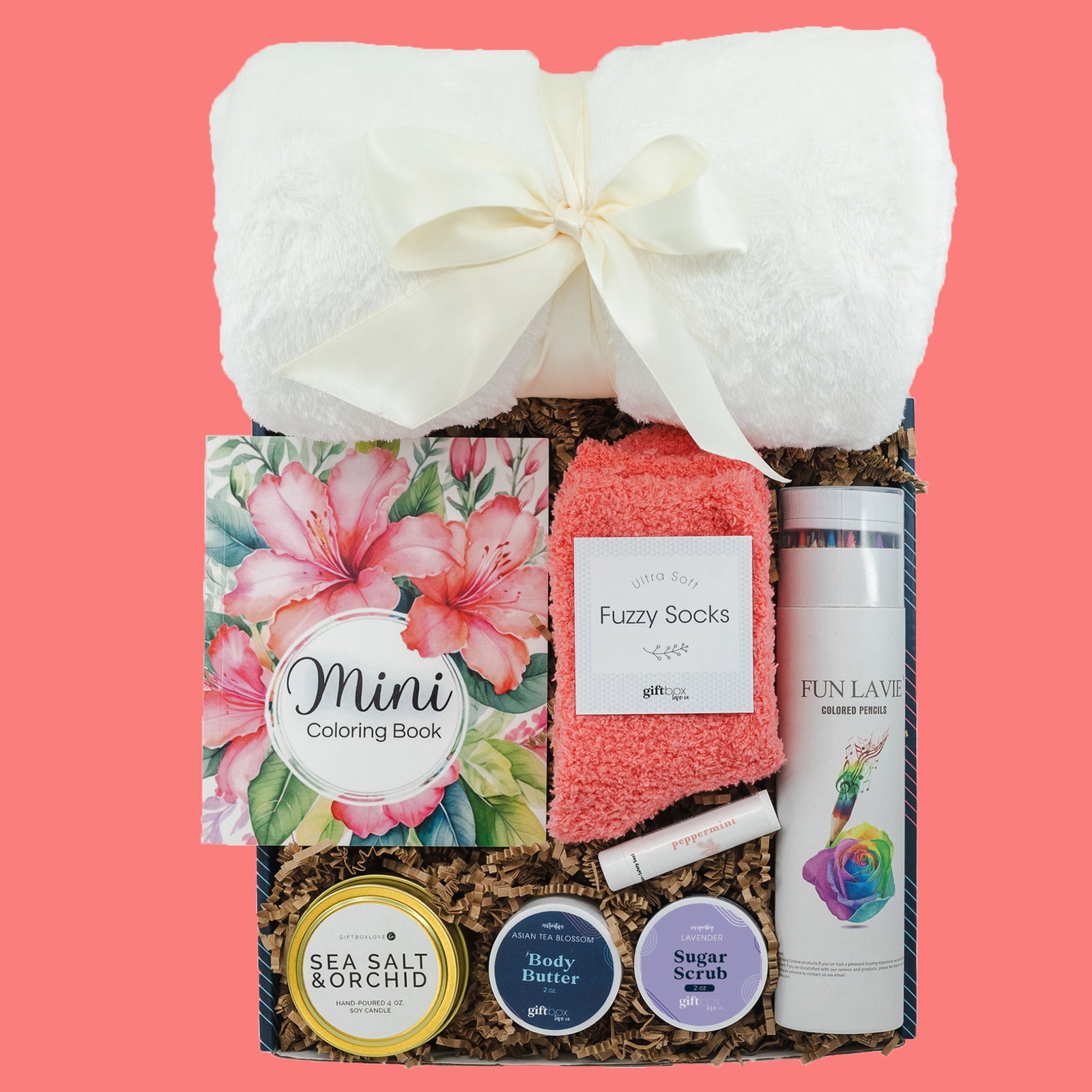 Creative Self-Care Gift Box featuring a soft blanket, cozy socks, soy candle, body butter, sugar scrub, chapstick, coloring book, and colored pencils for relaxation.