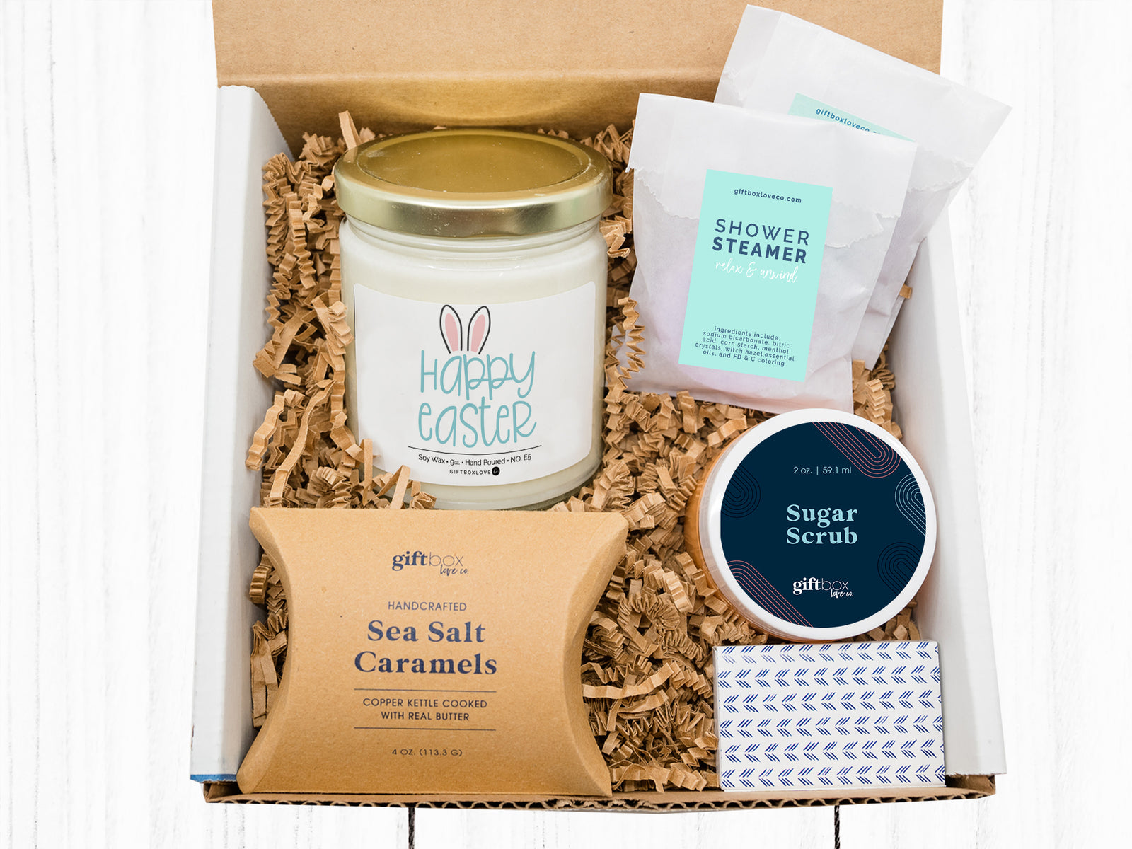 Happy Easter Gift Box featuring a 9 oz soy candle with faith-based label, sugar scrub, lavender shower steamers, caramels, matches, and handwritten card.
