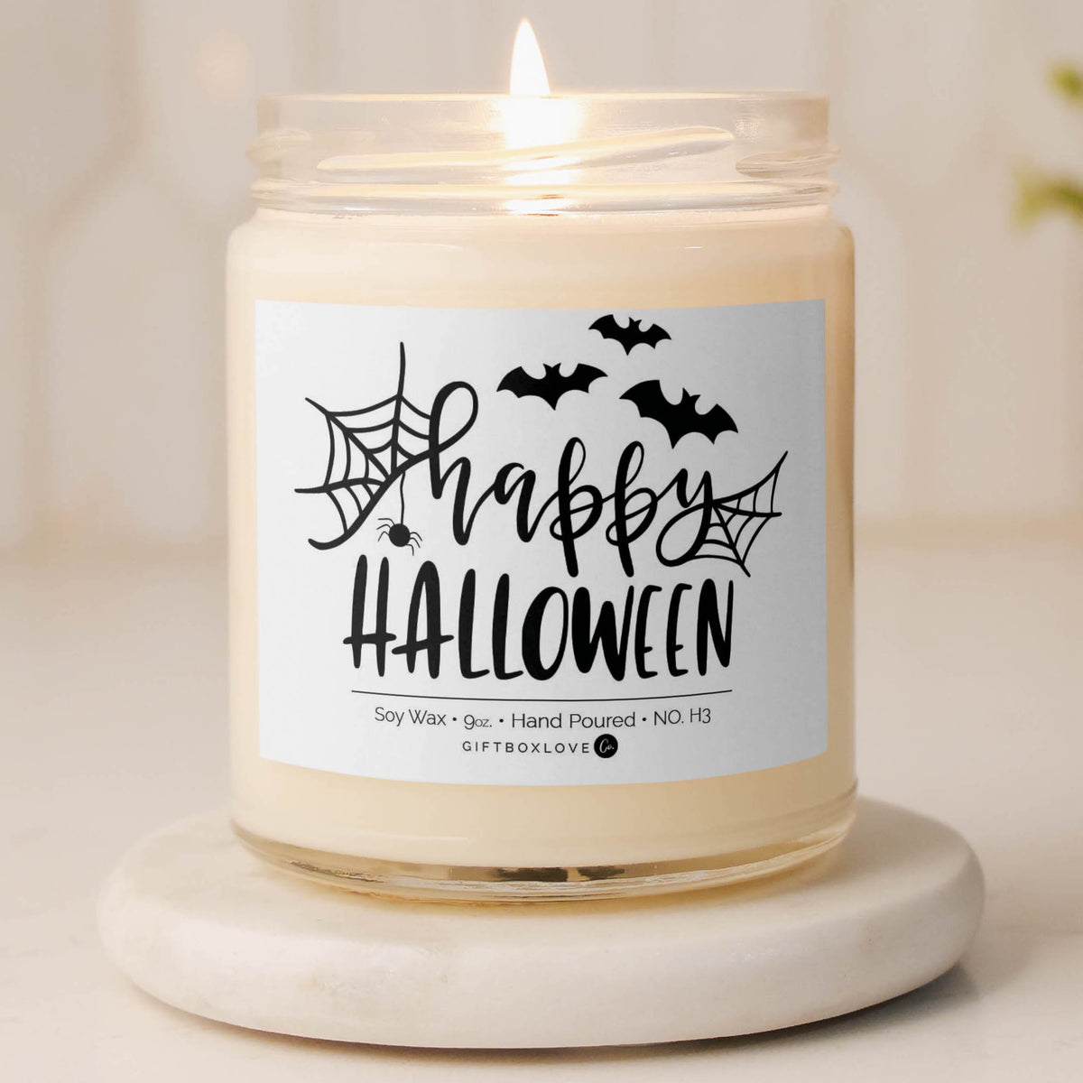Happy Halloween candle with black spider web and bat design