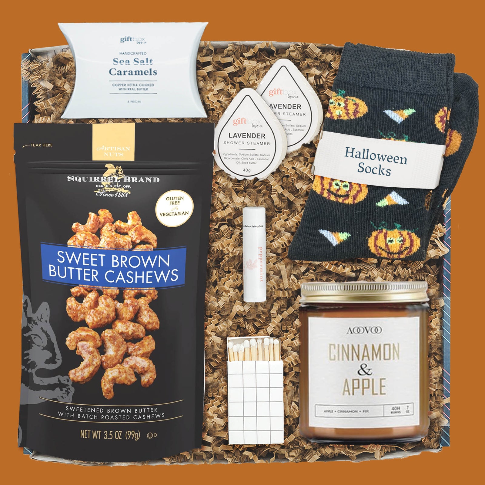 Harvest Treats & Cozy Care Gift Box with socks, candle, cashews, caramels, shower steamers, lip balm, and matches.