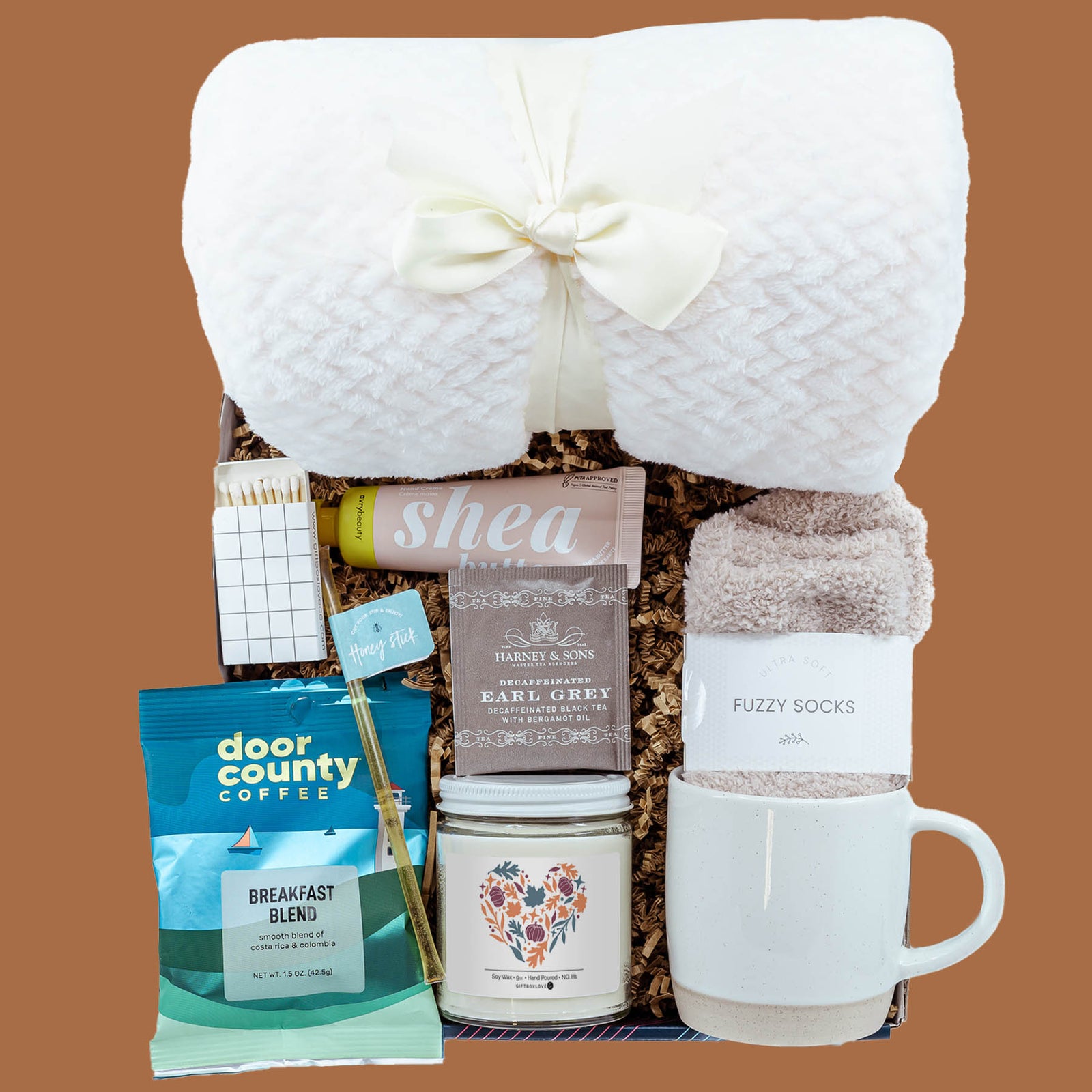 Leaves & Lattes Gift Box with plush blanket, stoneware mug, Door County Coffee, Earl Grey tea, fuzzy socks, shea butter hand cream, autumn soy candle, honey stick, and decorative matches.