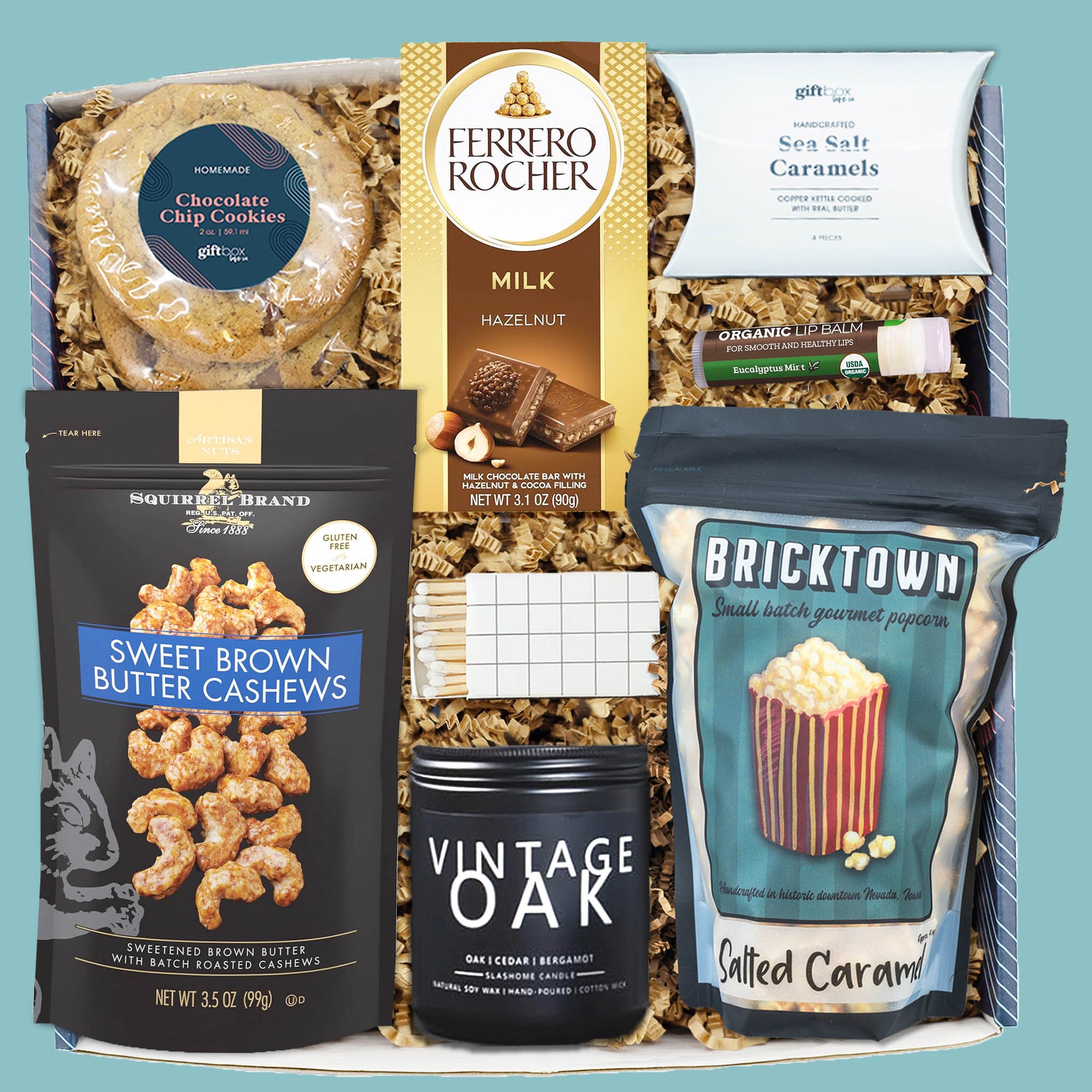 Men’s cozy snack box with cookies, cashews, popcorn, caramels, chocolate bar, and oak candle.
