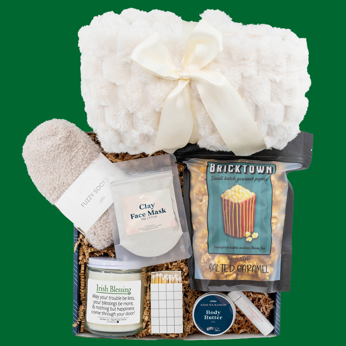 St. Patrick’s Night In gift box with plush blanket, salted caramel popcorn, Irish Blessing candle, fuzzy socks, and spa items.