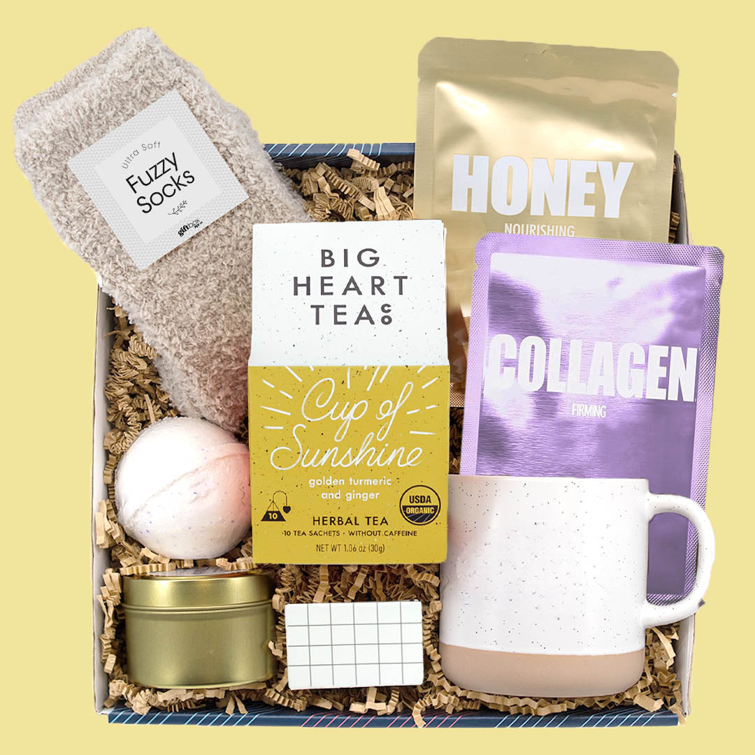 Sunshine care package gift box with tea, mug, socks, face masks, bath bomb, and candle.