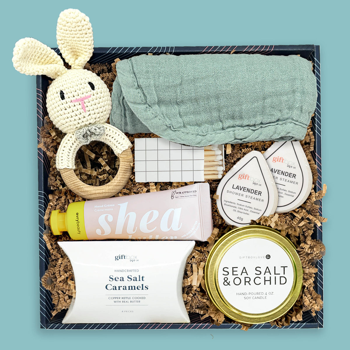 Baby gift box with crochet bunny rattle, muslin burp cloth, candle, and baby essentials