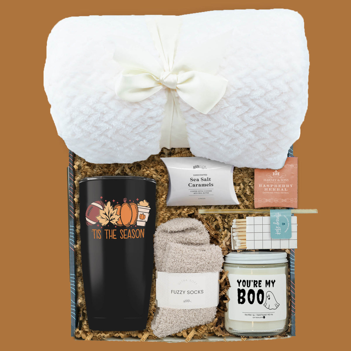 Tiss the Season Gift Box with blanket, festive tumbler, candle, fuzzy socks, tea, caramels, and matches.